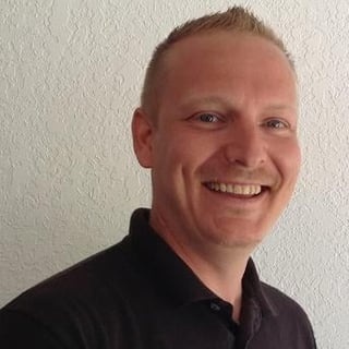 Smiling man with short reddish hair wearing a dark shirt
